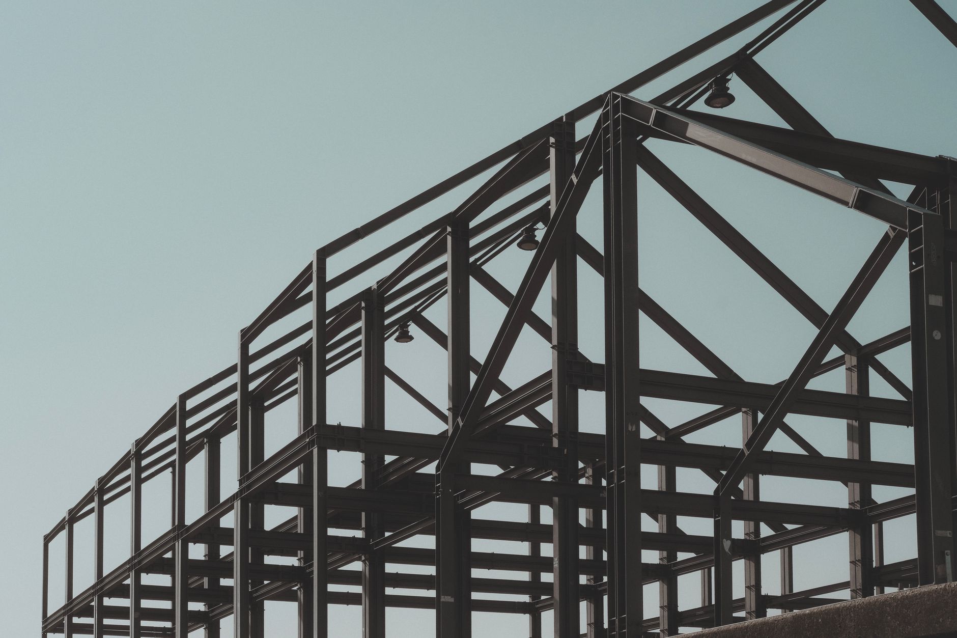 Structural steel roof framework under construction against a blue sky
